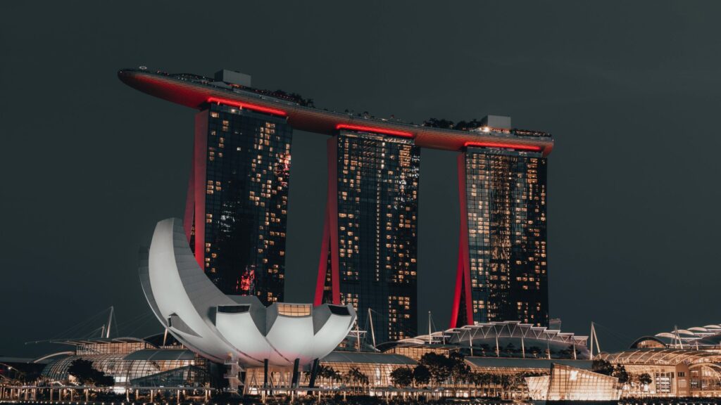 Night view of Marina Bay Sands in Singapore, illuminated with red and white lights, showcasing the city's iconic luxury and architectural brilliance.